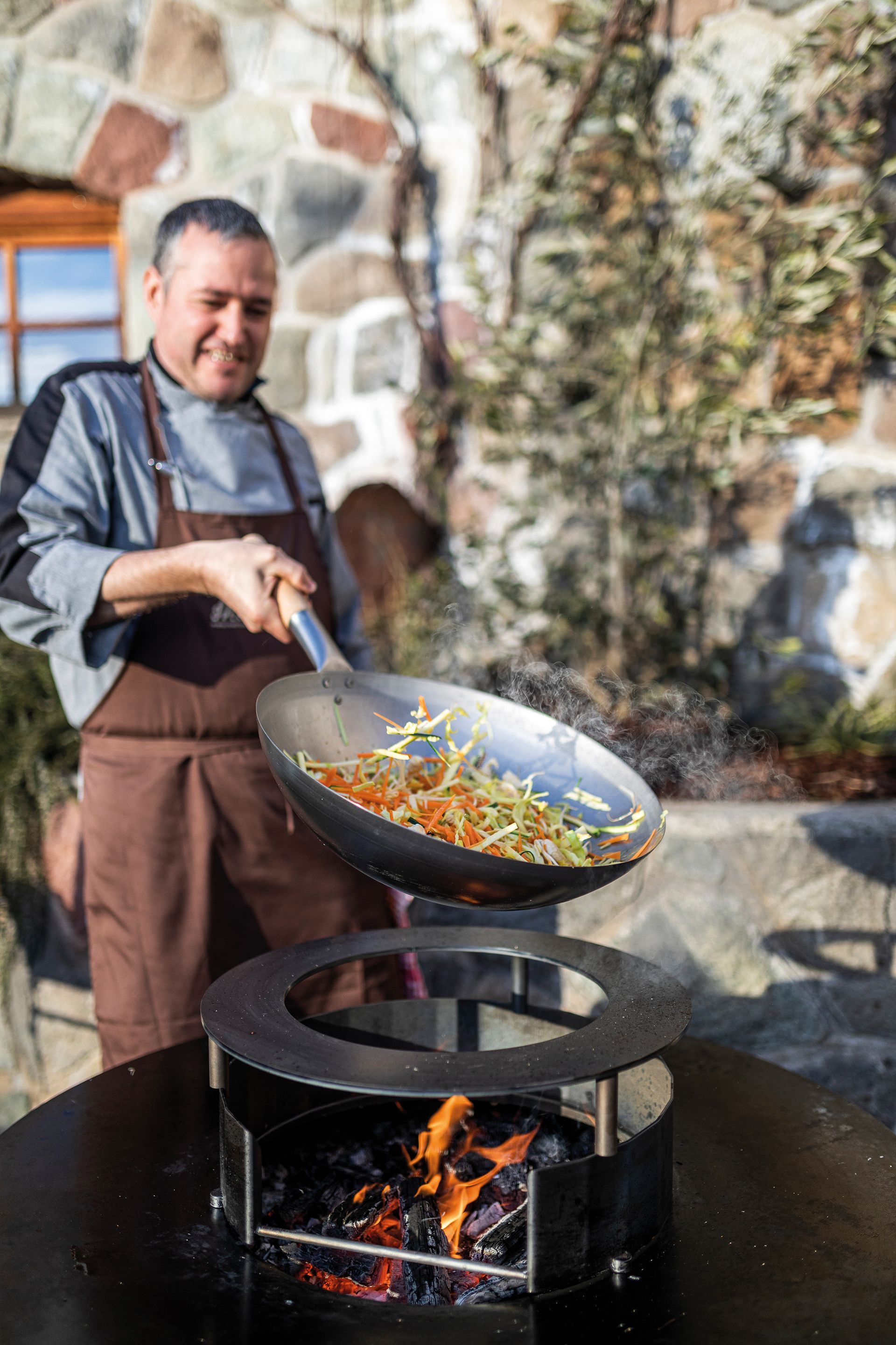 Mann kocht mit Wokpfanne und Feuerring von Martin Deuflhart