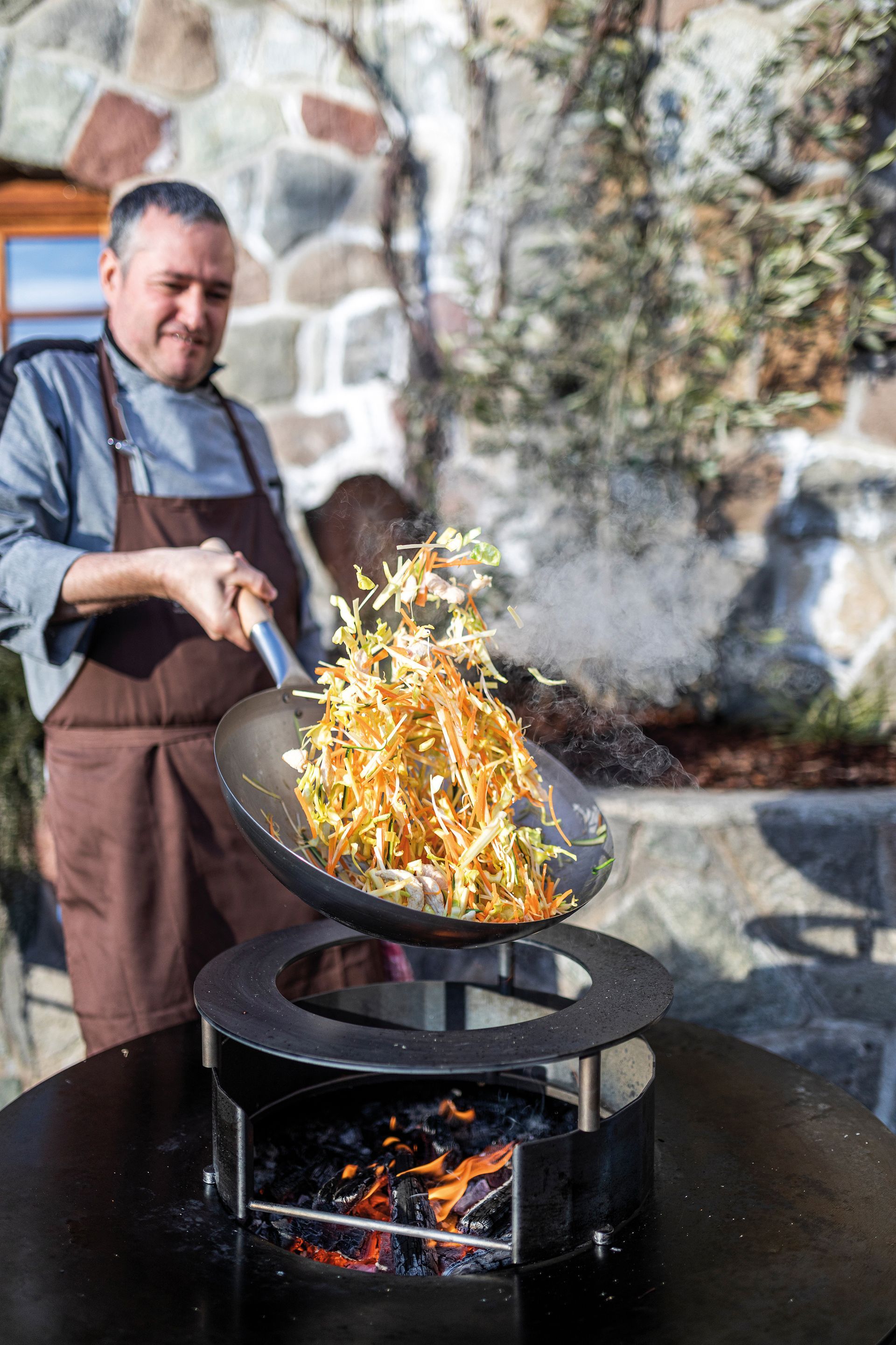 Mann kocht mit Wokpfanne und Feuerring von Martin Deuflhart