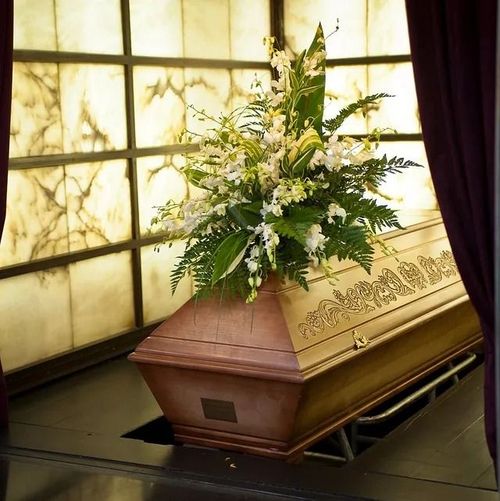 Un ataúd de madera con flores encima.