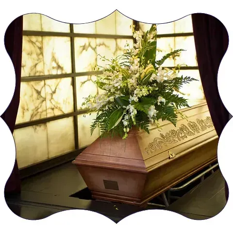Un ataúd con flores encima delante de una ventana.
