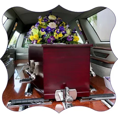 Un ataúd con flores moradas y amarillas dentro.
