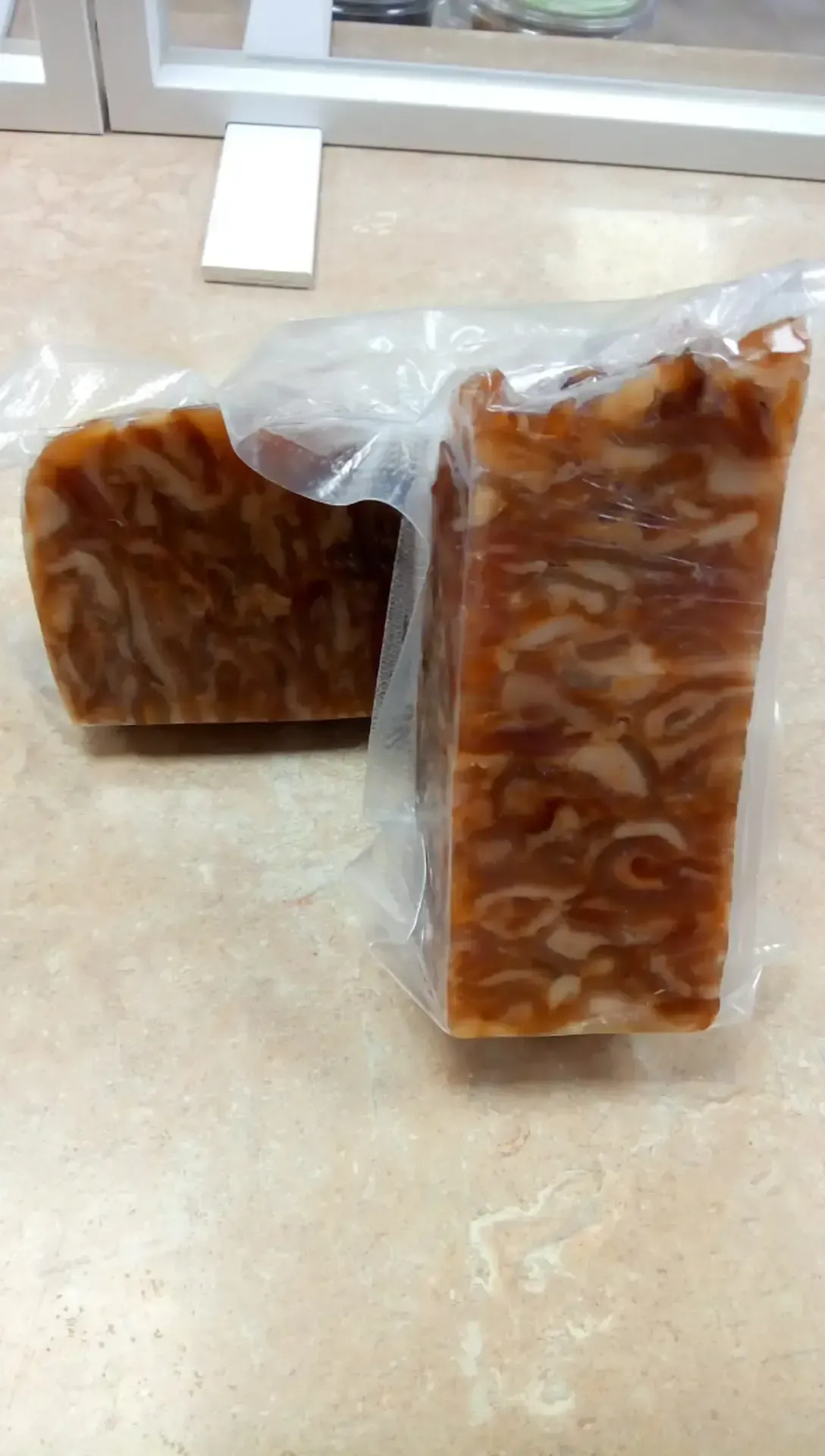 Dos piezas de jabón están envueltas en plástico y colocadas sobre una mesa.