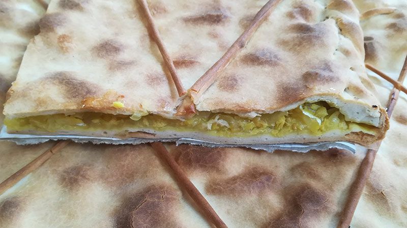 Un trozo de pizza está encima de un trozo de pan en una mesa.