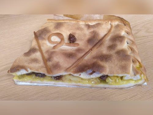 Un trozo de pizza está sobre una mesa de madera.