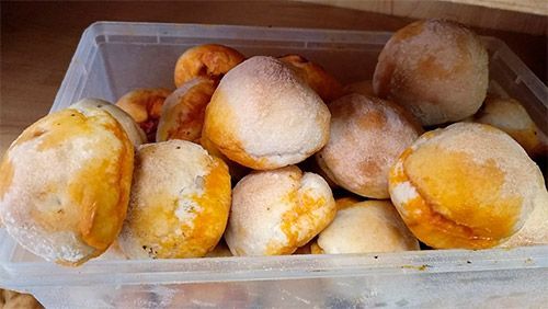 Un recipiente de plástico lleno de panecillos sobre una mesa.