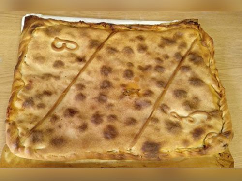 Un gran trozo de pizza está sobre una mesa de madera.