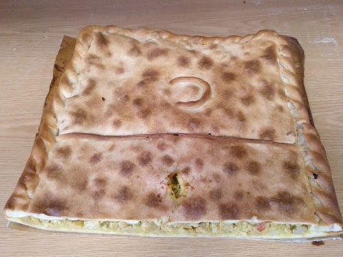 Una pizza con un agujero en el medio está sobre una mesa de madera.