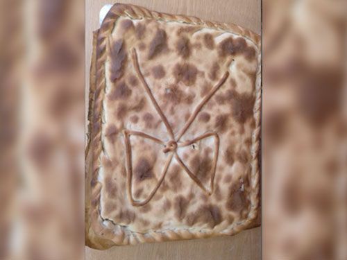 Un trozo de pan con un lazo encima está sobre una mesa de madera.