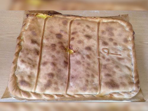 Una pizza grande está sobre una mesa de madera.