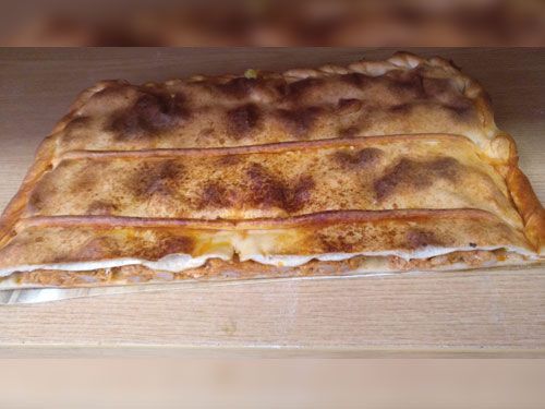 Una pizza está encima de una mesa de madera.