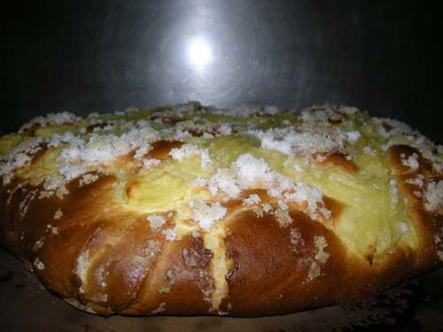 Sobre una mesa hay una hogaza de pan con azúcar en polvo encima.