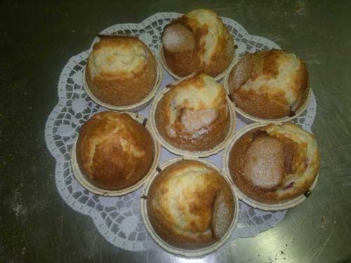 Un montón de muffins están colocados sobre una servilleta de encaje sobre una mesa.