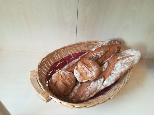 Una cesta llena de pan está sobre una mesa.