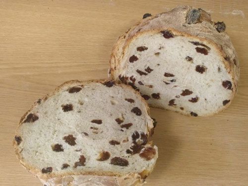 Dos rebanadas de pan con pasas están sobre una mesa de madera.