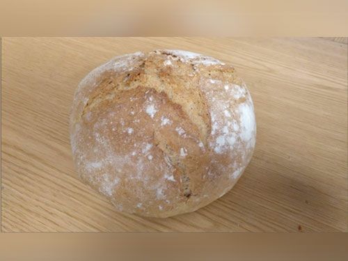 Una hogaza de pan está sobre una mesa de madera.