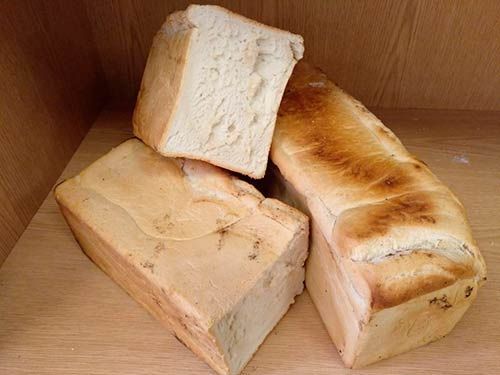 Tres barras de pan están apiladas una encima de otra sobre una mesa de madera.