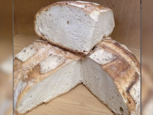 Una hogaza de pan está colocada encima de otra hogaza de pan sobre una mesa de madera.