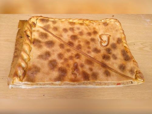 Un trozo de pizza está sobre una mesa de madera.