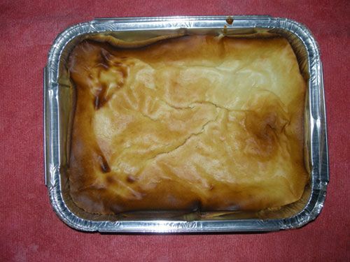 Una bandeja de aluminio llena con un trozo de comida sobre una mesa.