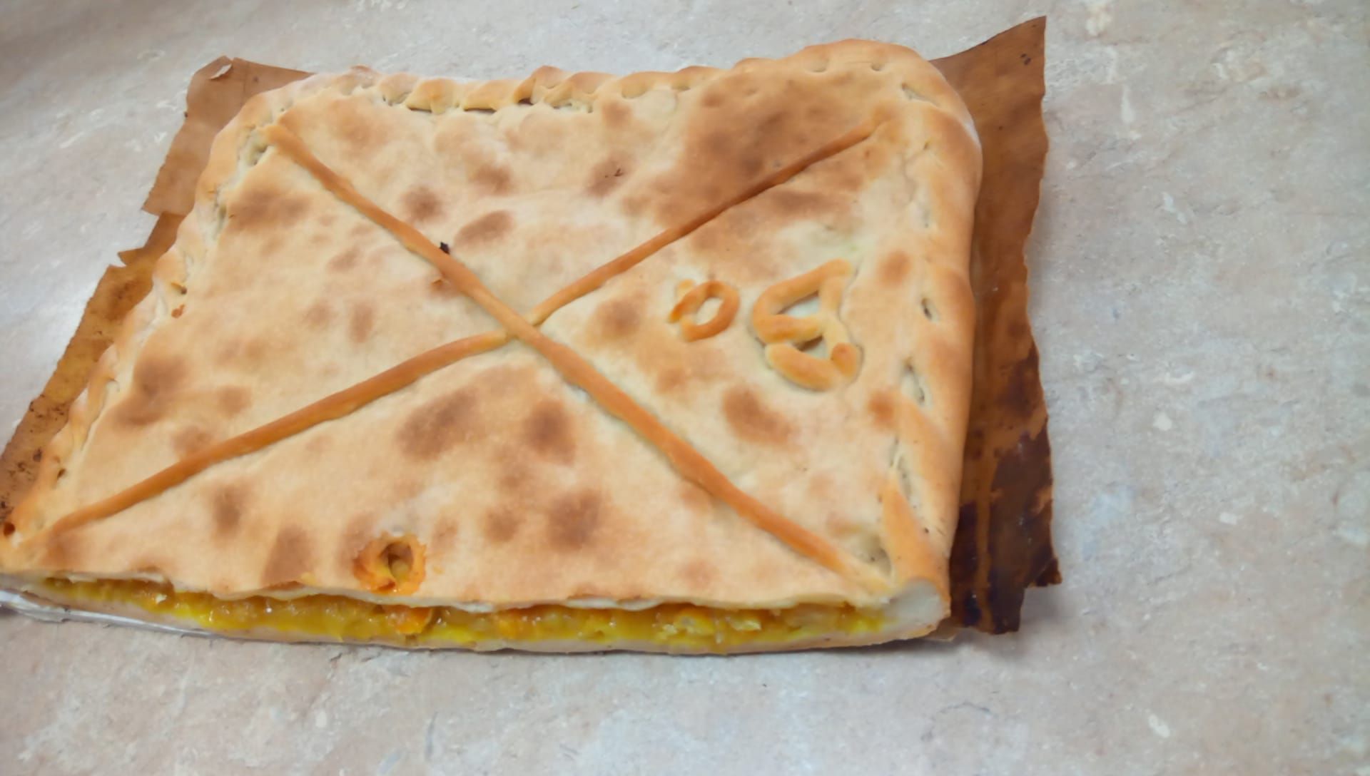 Una pizza con una cruz está sobre una mesa.