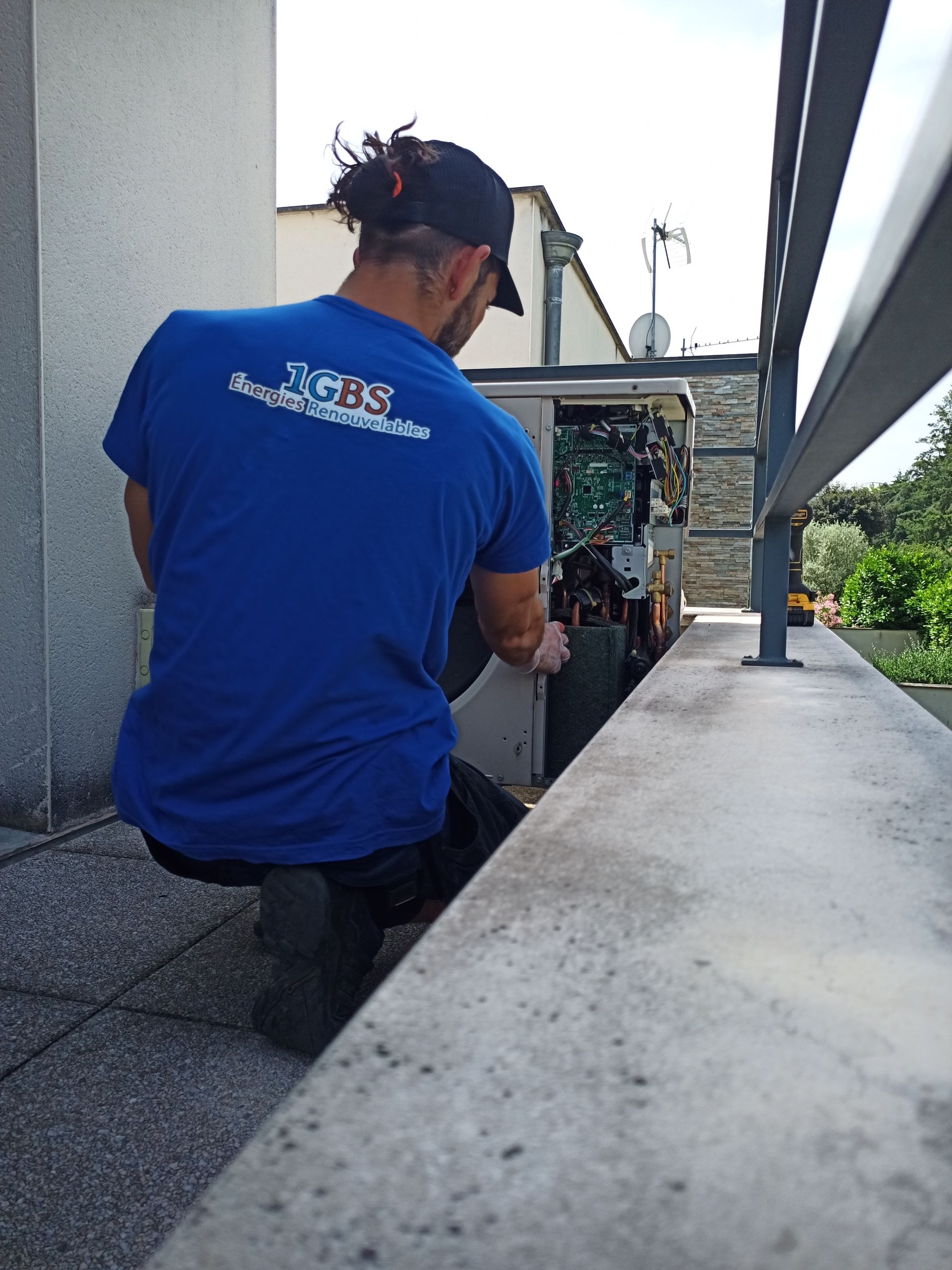 Plombier-chauffagiste en pleine installation d'une pompe à chaleur sur un balcon