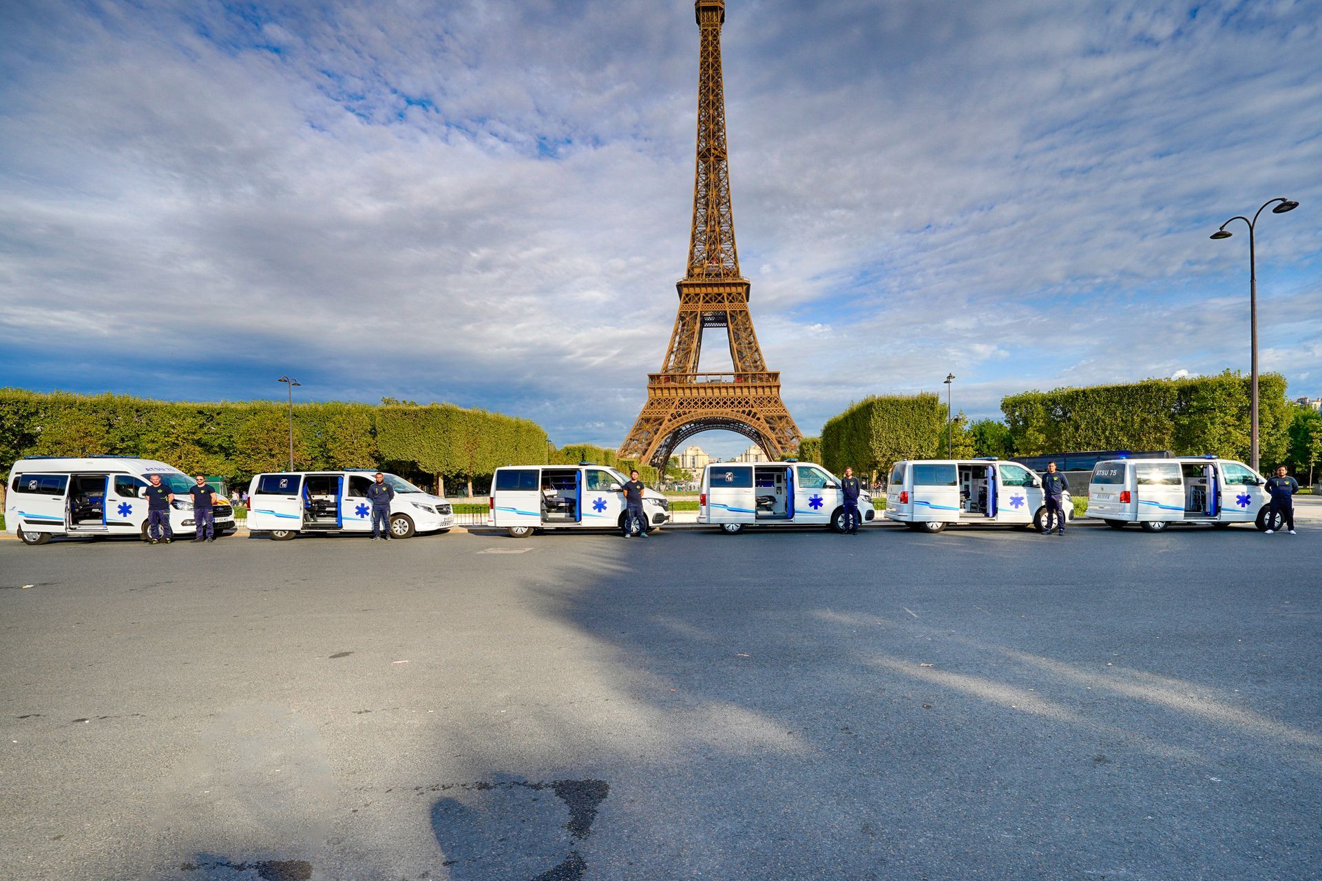 Ambulanciers pris en photo devant leur véhicule et la tour Eiffel