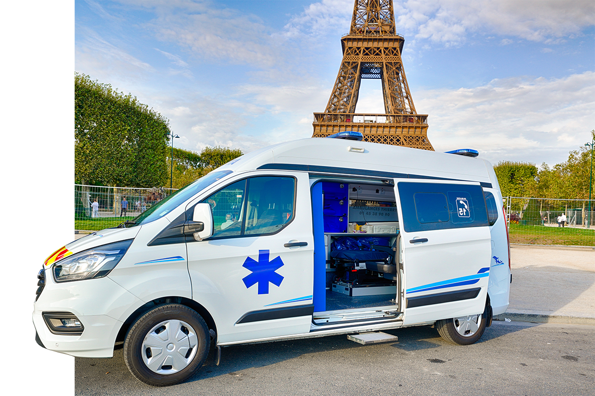 Ambulance avec la porte latérale ouverte devant la tour Eiffel