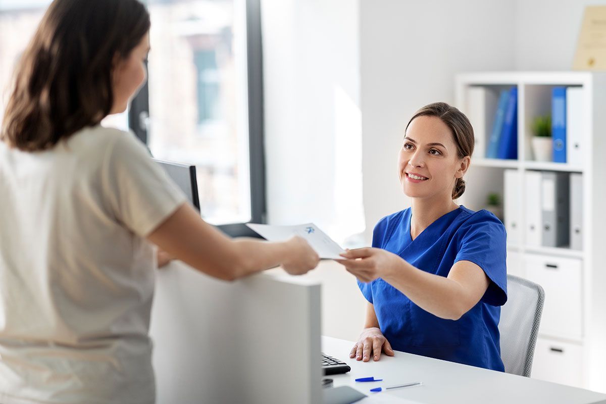Femme qui donne sa feuille de soin à une secrétaire de santé