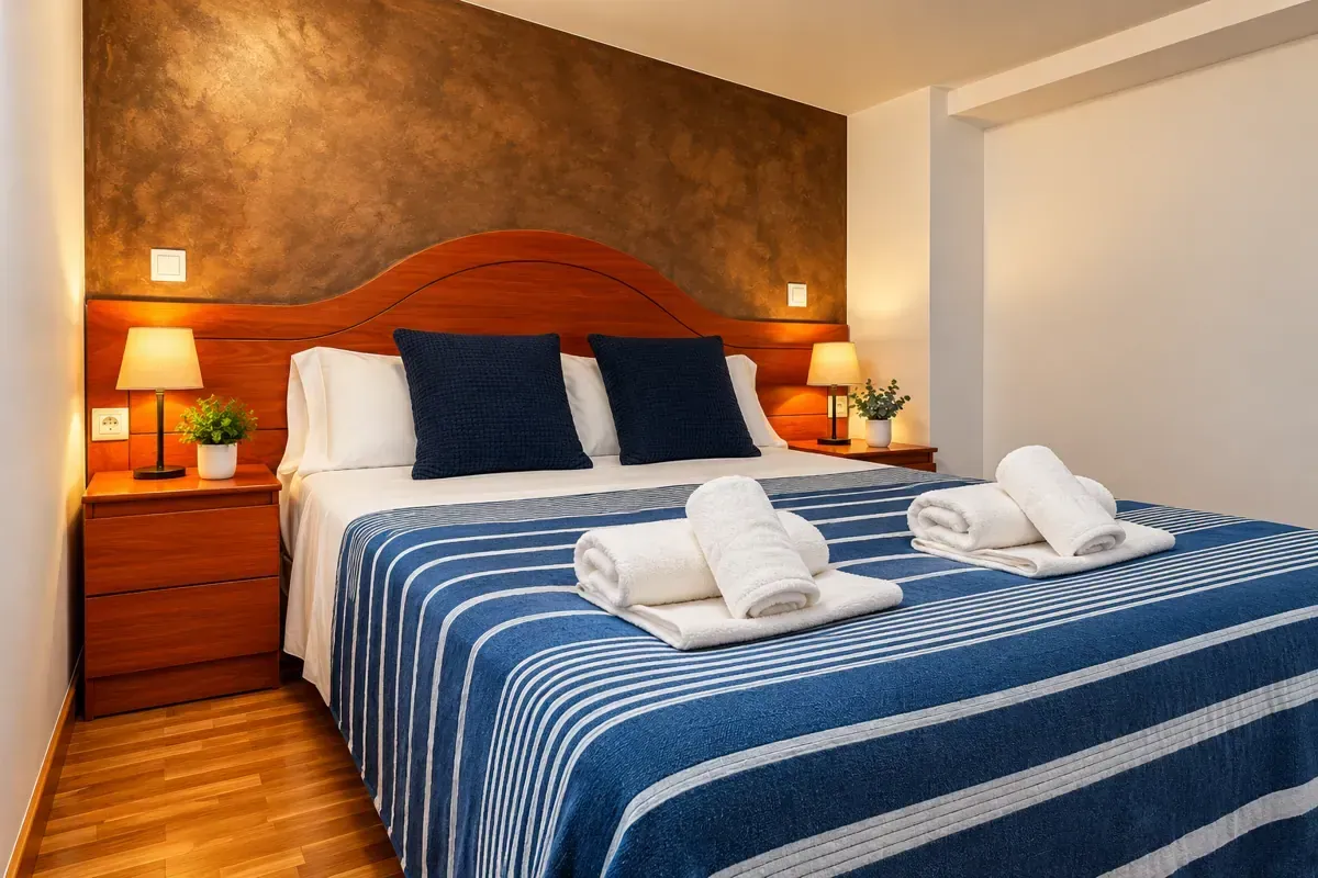 Dormitorio moderno con una cama, un escritorio, iluminación cálida y suelo de madera