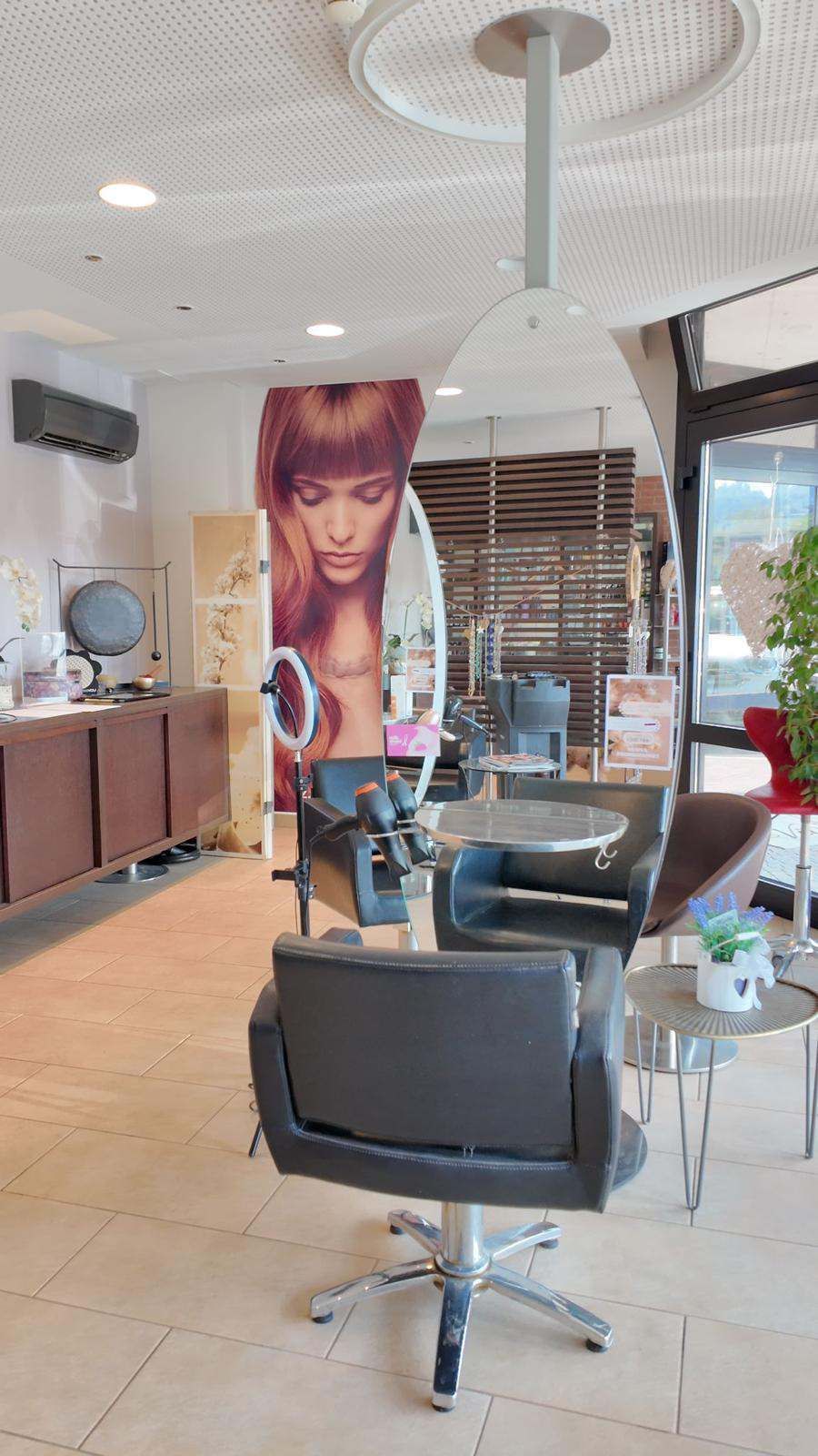 Interno di un salone con poltrone da parrucchiere, specchi e un grande poster con un ritratto appeso alla parete.