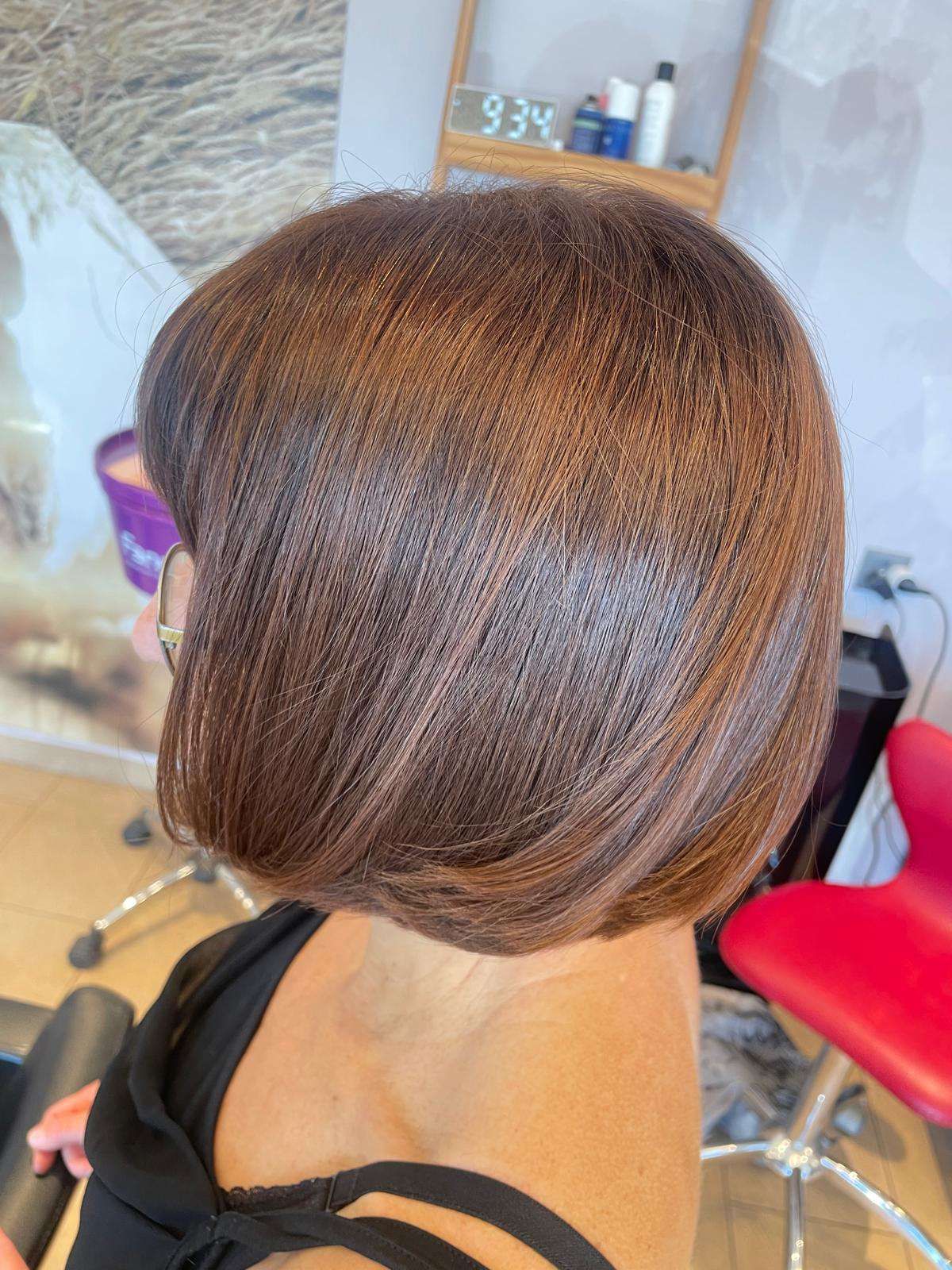 Taglio di capelli corto a caschetto castano in un salone, visto di profilo.