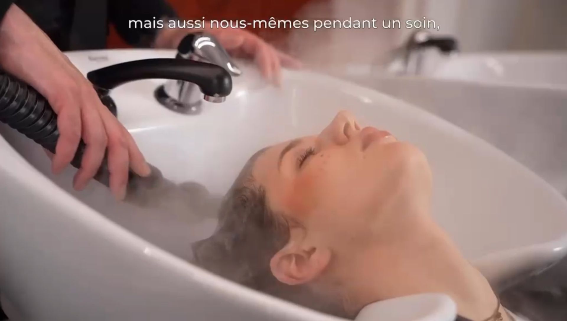 Una persona è sdraiata in una vasca da bagno bianca mentre l'acqua scorre da un rubinetto sopra di lei.