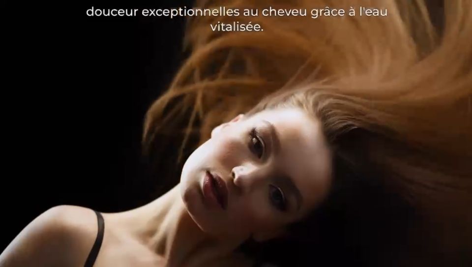 Primo piano di una donna dai capelli fluenti sdraiata su uno sfondo scuro, con testo in francese sopra.
