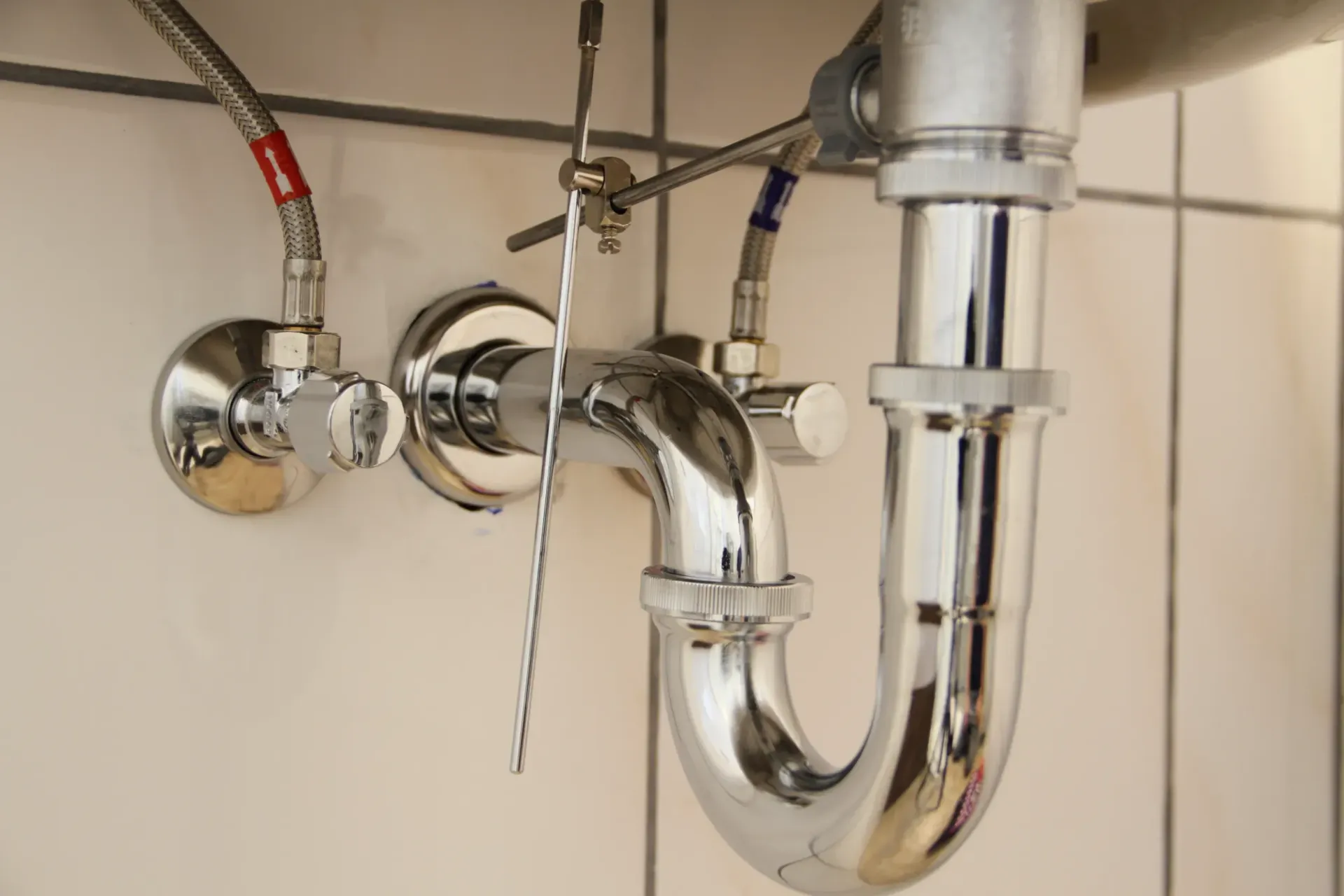 Un primer plano de una tubería de plomería debajo de un lavabo en un baño.