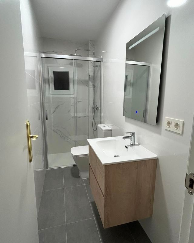 Un baño con lavabo, inodoro, ducha y espejo.
