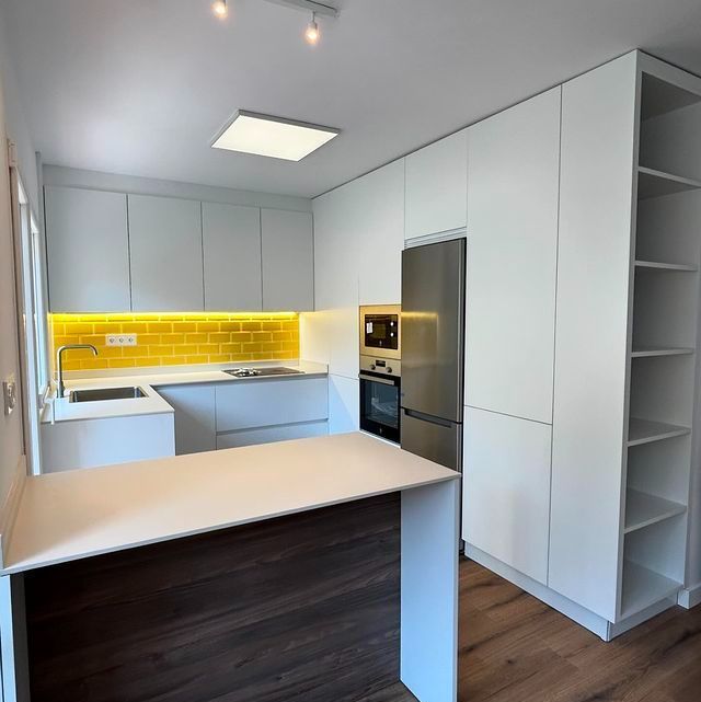 Una cocina con gabinetes blancos y electrodomésticos de acero inoxidable.