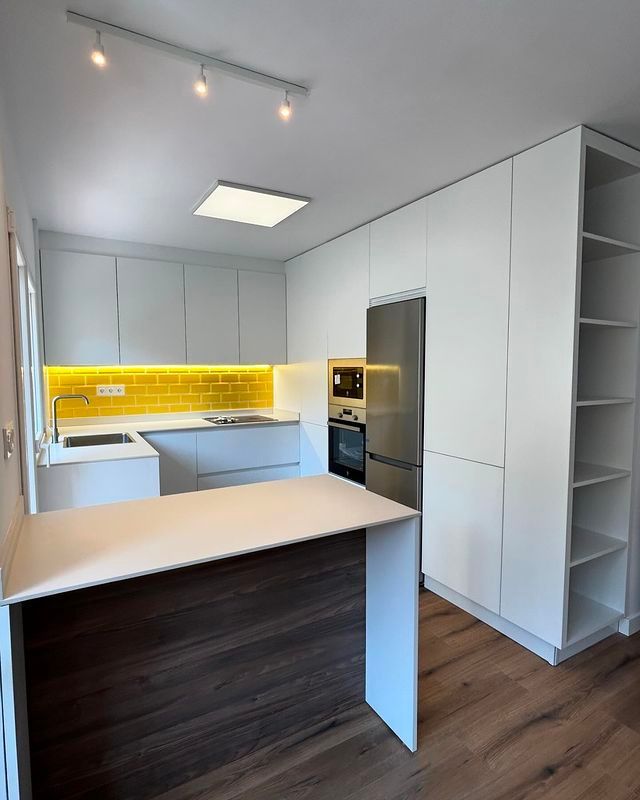Una cocina con gabinetes blancos y electrodomésticos de acero inoxidable.