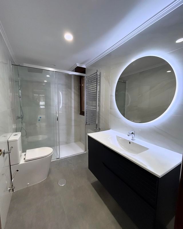Un baño con inodoro, lavabo, ducha y espejo.