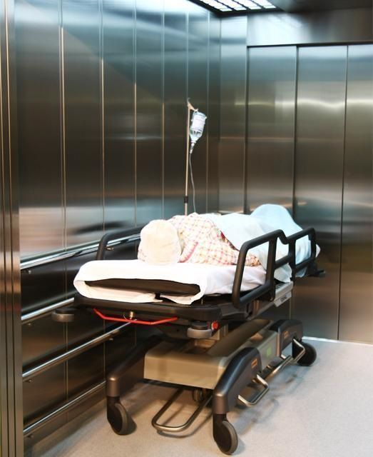 Una cama de hospital en un ascensor con un goteo conectado a ella.