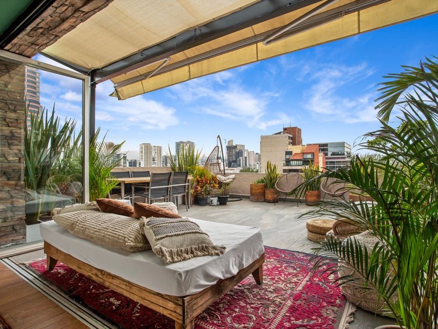 A patio with a bed and a rug and a view of the city.