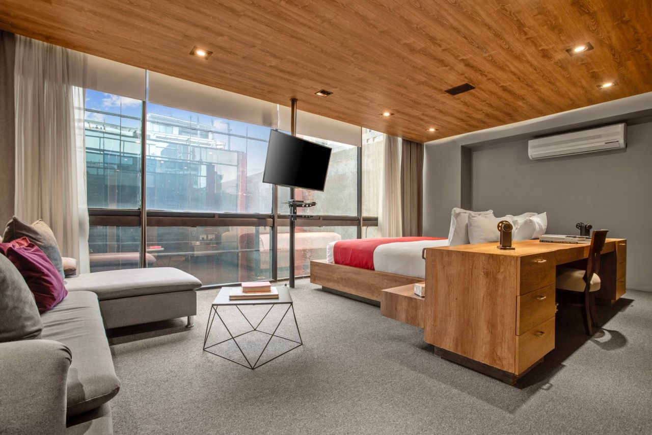 A hotel room with a bed , couch , desk and television.