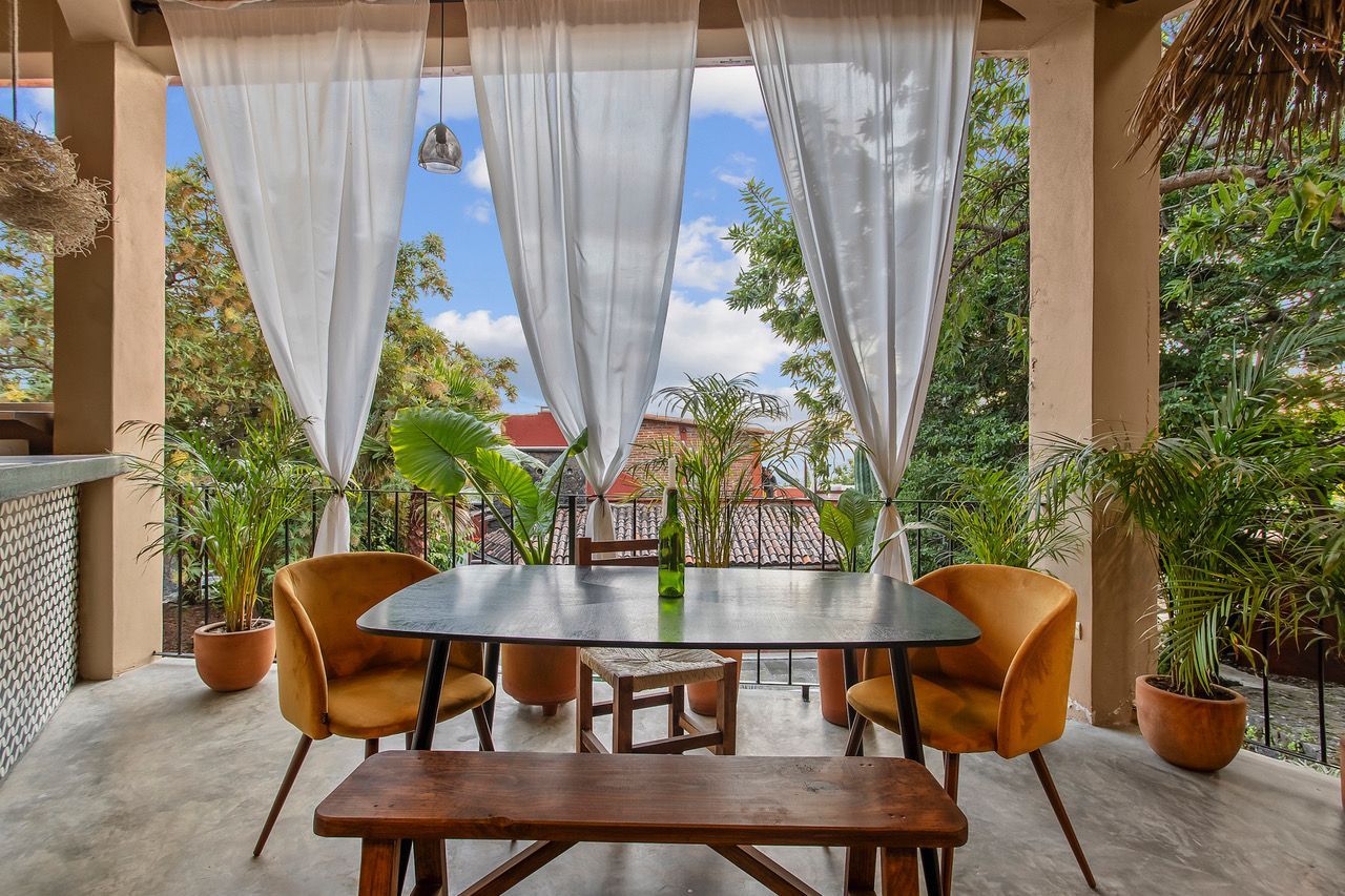 There is a table and chairs on the balcony with curtains.