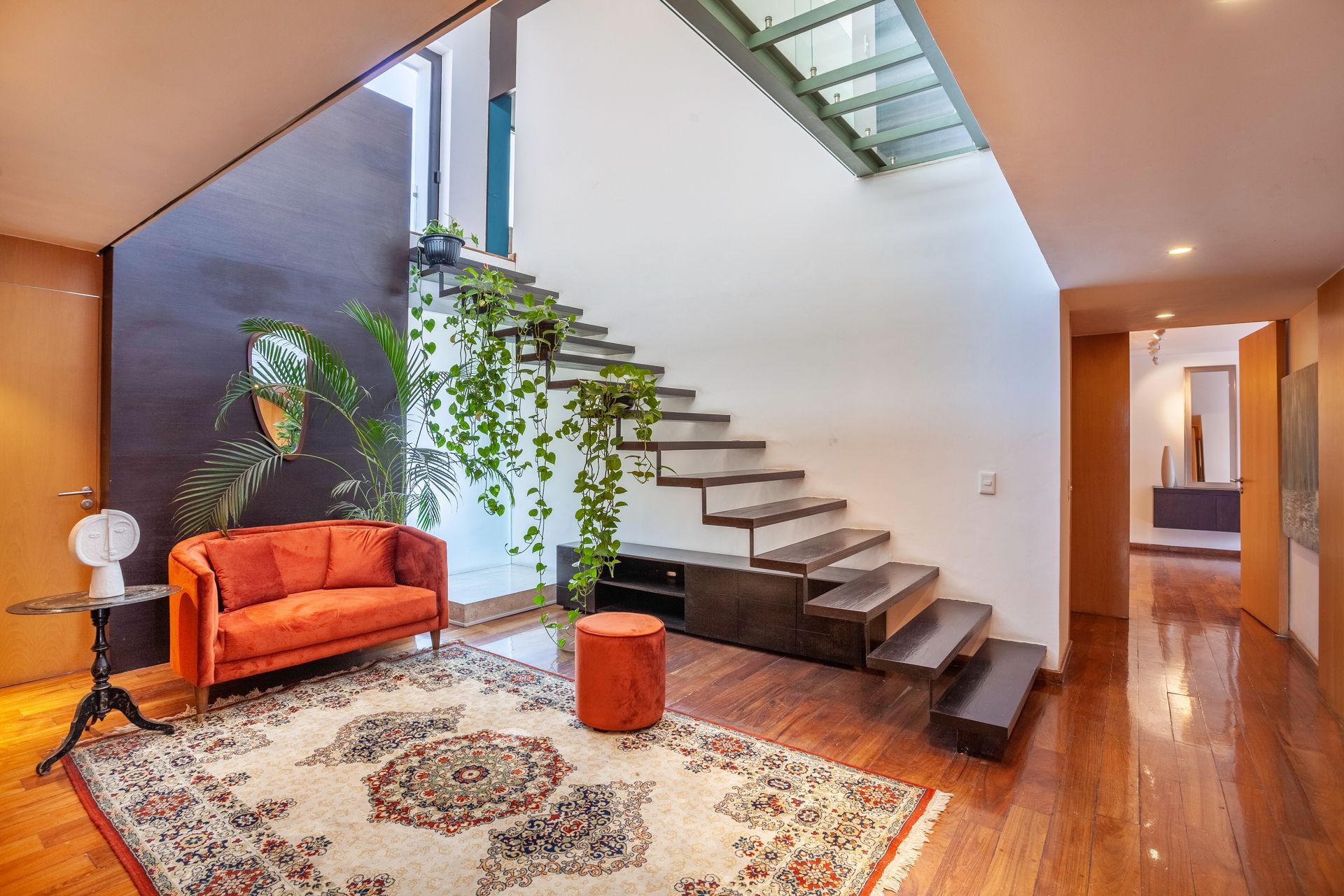 A living room with a couch , rug and stairs.