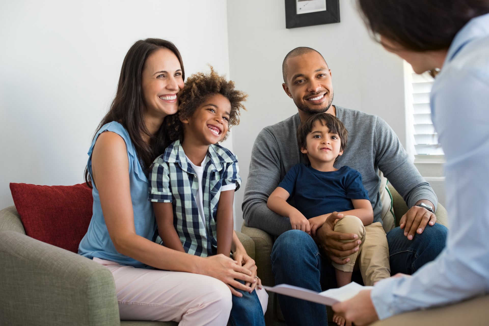 Une famille discute avec un conseiller sur un canapé dans un salon lumineux