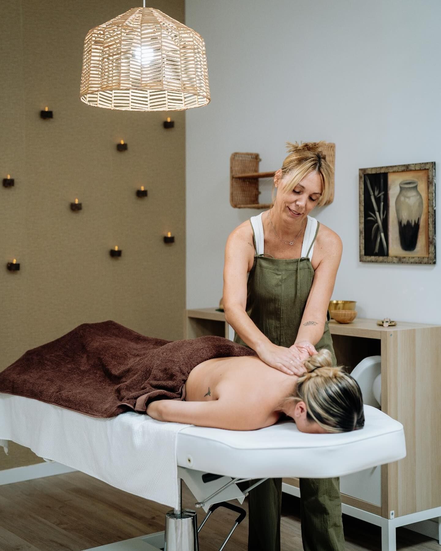 Una mujer le está dando un masaje a una mujer acostada en una mesa de masajes.