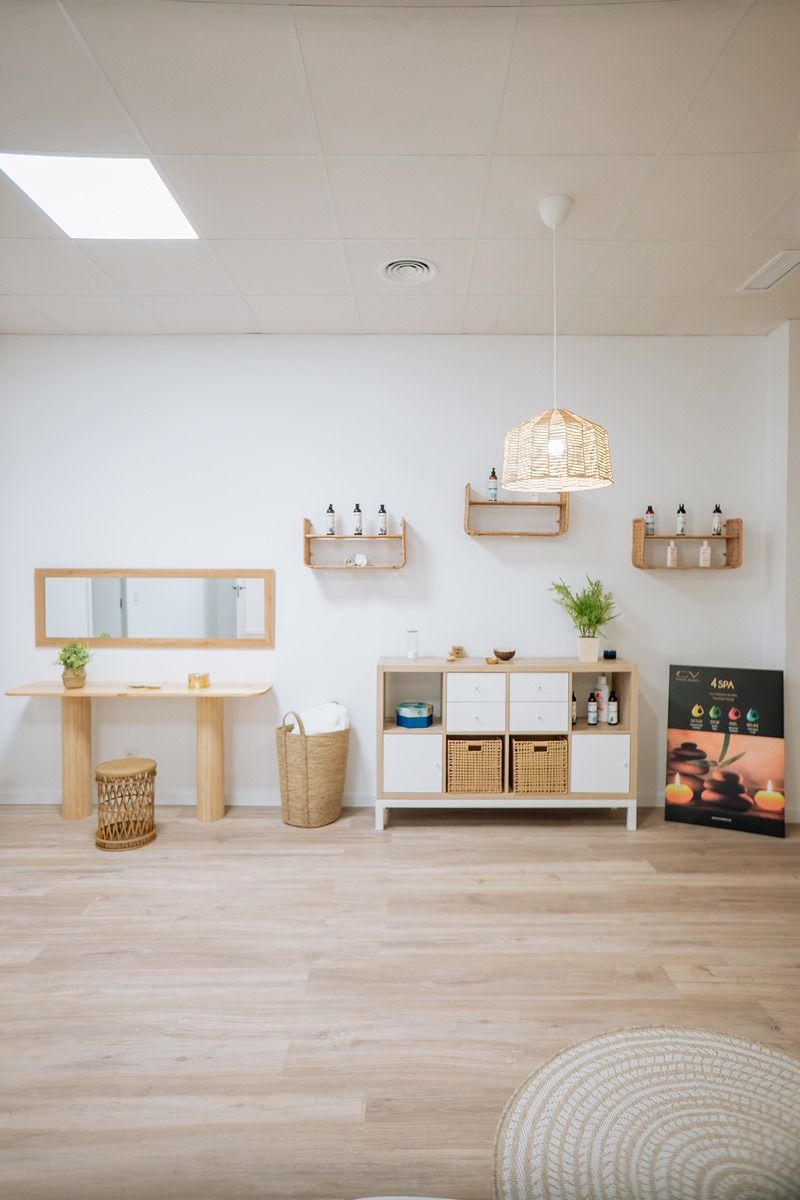 Una sala de estar con suelo de madera, paredes blancas, un espejo y un estante.