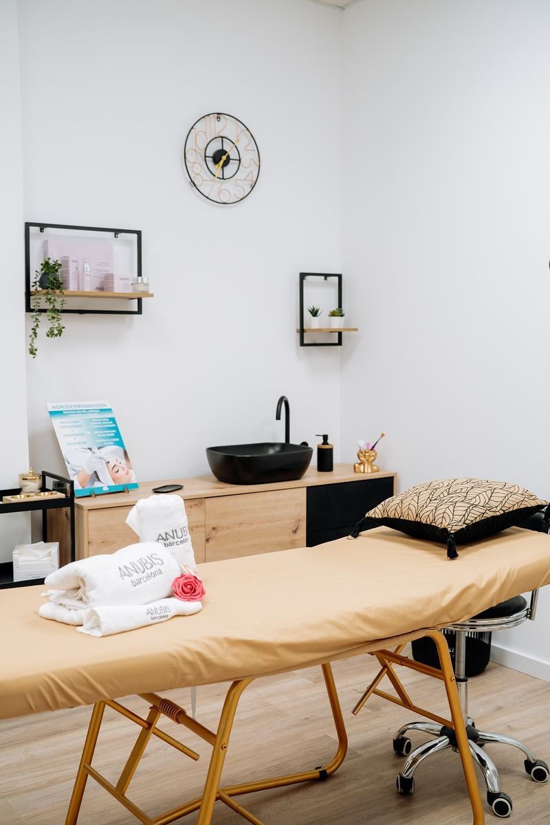 Una mesa de masajes en una habitación con un lavabo y un reloj en la pared.