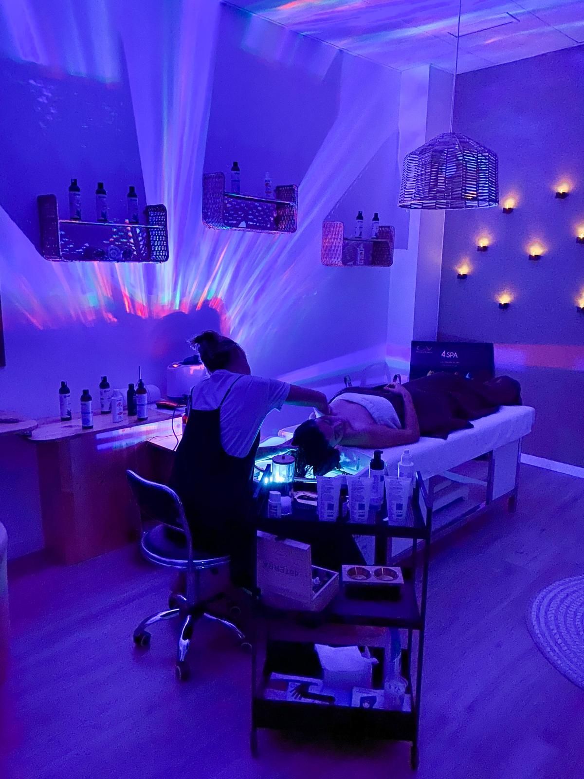 Una mujer está recibiendo un masaje en una habitación con luces violetas.