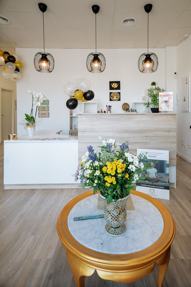 Una mesa con un jarrón de flores delante de un mostrador de recepción.