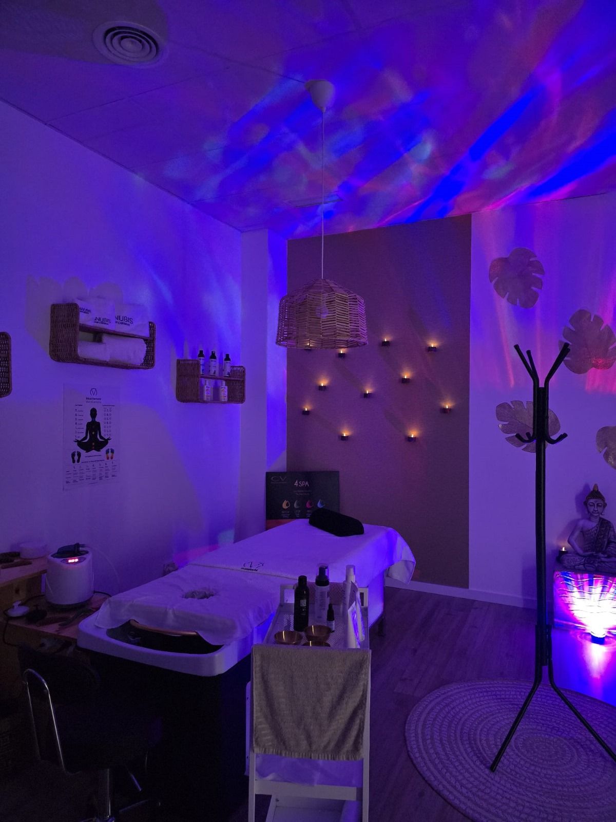 Una mesa de masajes en una habitación oscura con luces violetas.